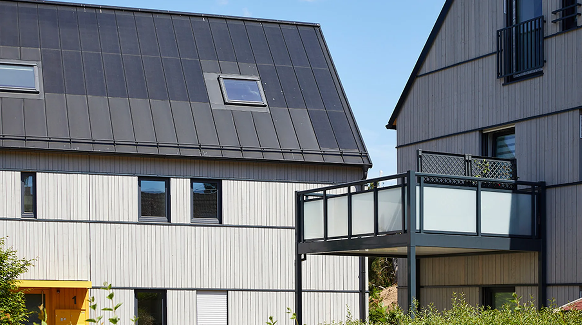 Nachhaltig modernisierte Wohnhäuser mit klar strukturierter Holzfassade, großen Fenstern und Balkon