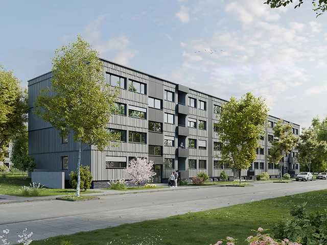 Modern apartment building with gray facade, surrounded by trees and greenery. A sidewalk and parked cars line the street under a partly cloudy sky.